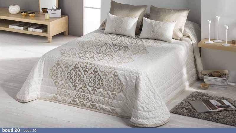 Una cama con edredón y almohadas en un dormitorio.