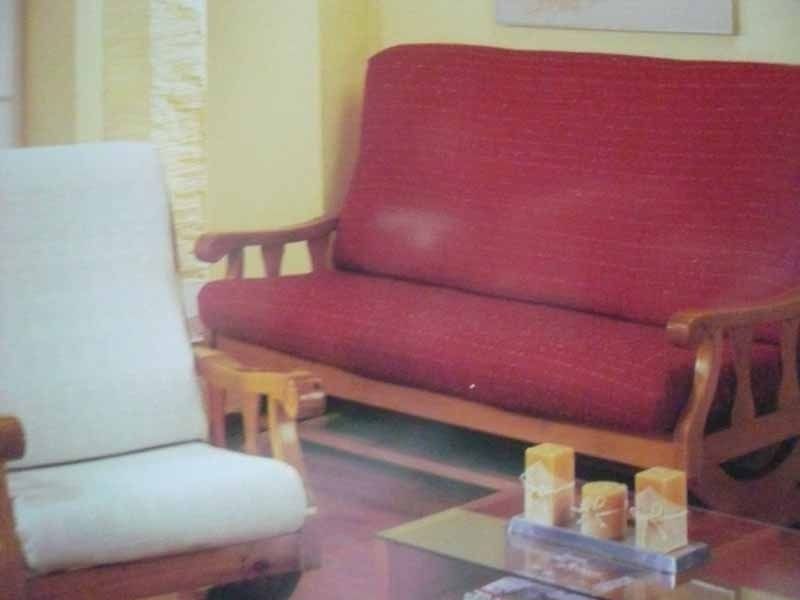 Una sala de estar con un sofá rojo y una silla blanca.