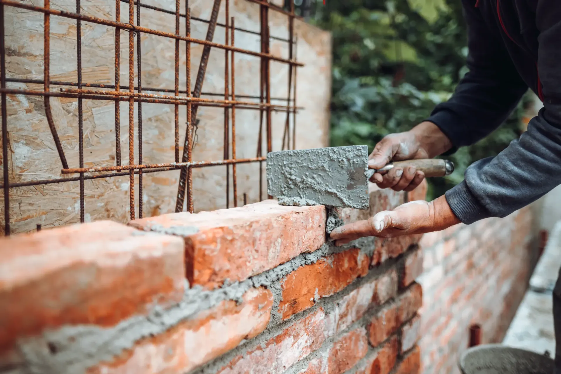 Un hombre está colocando ladrillos en una pared con una paleta.