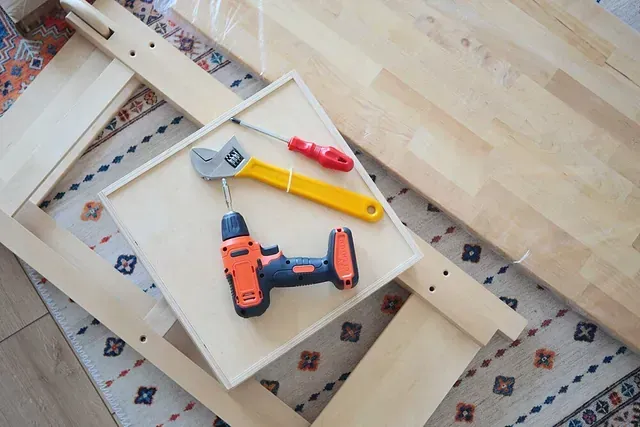 Un taladro y una llave inglesa están encima de una mesa de madera.