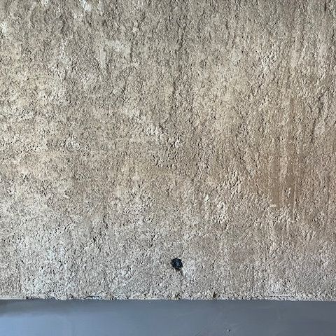 Mur extérieur avec la finition brute tirée à la règle crantée.