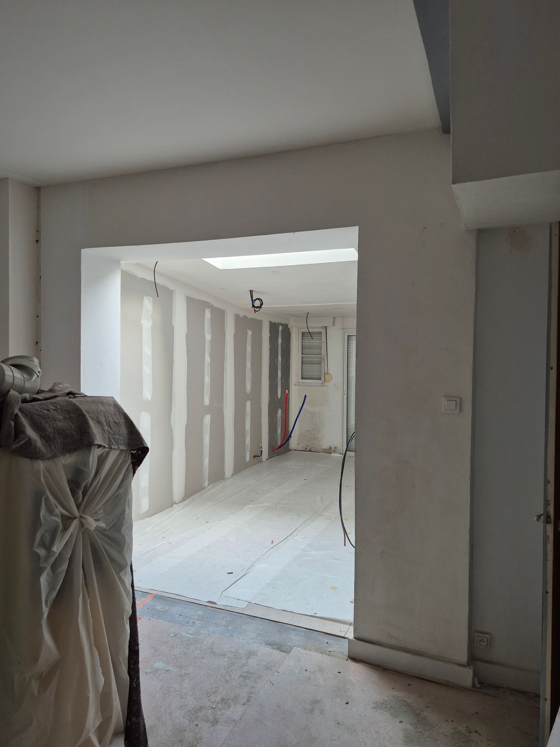 Aménagement intérieur, porte ouverte donnant sur un couloir avec charpente apparente et cloisons sèches.