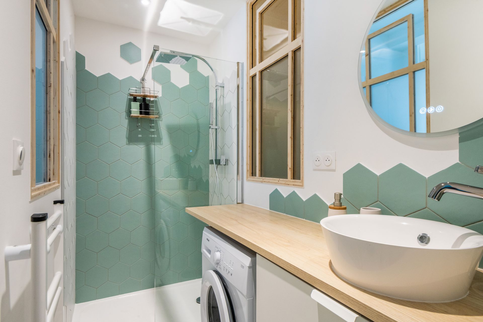 Petite salle de bains avec douche carrelée verte, lavabo blanc et machine à laver.