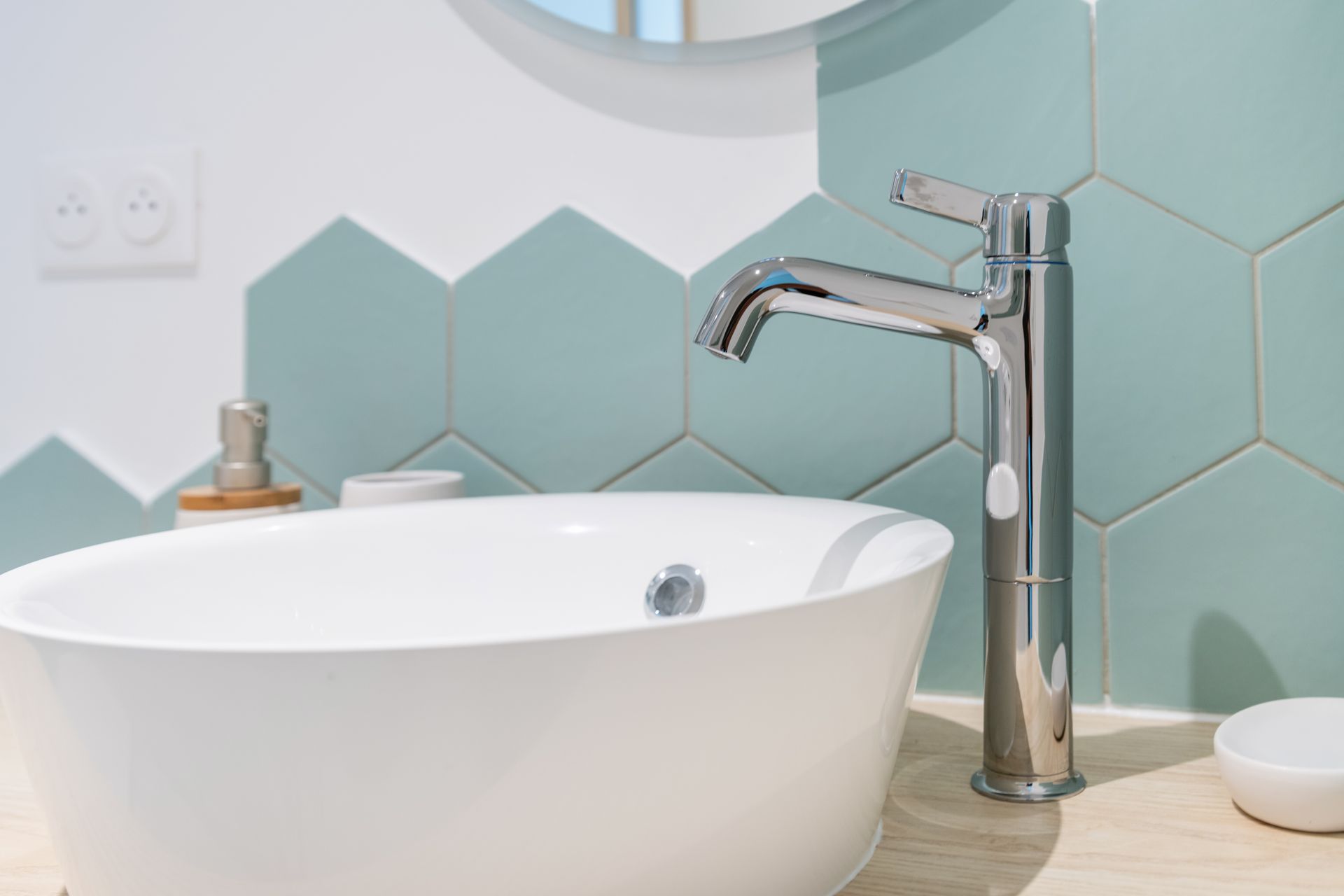 Lavabo blanc avec robinet chromé haut, sur un carrelage alvéolé bleu sarcelle.