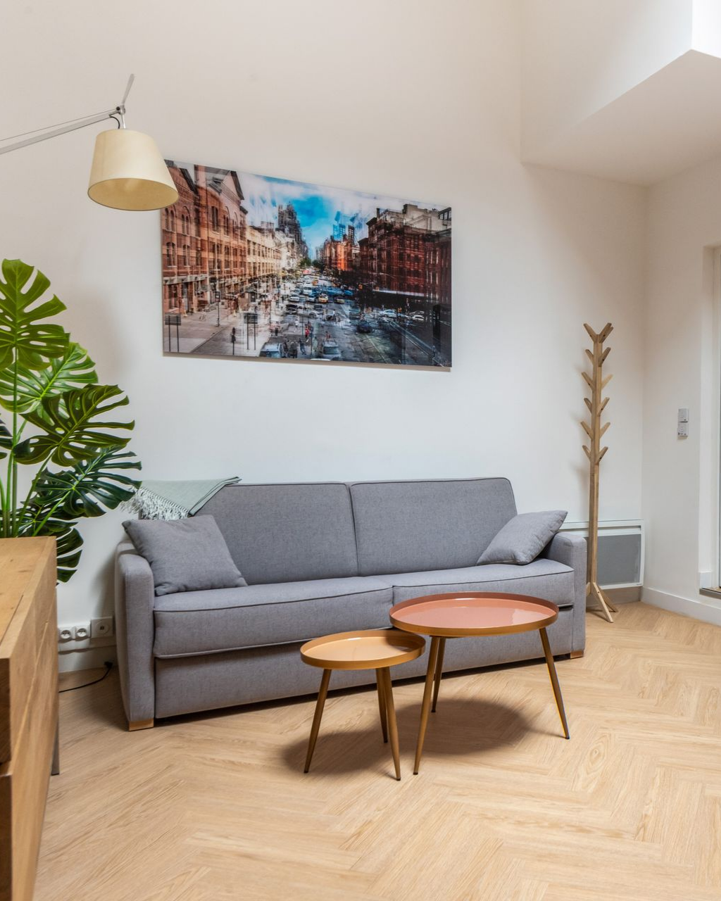 Canapé gris, deux petites tables et œuvres d'art dans un salon moderne.