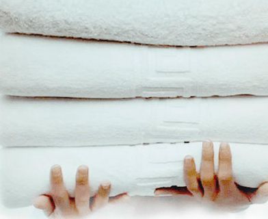 Una persona sostiene una pila de toallas blancas en sus manos.