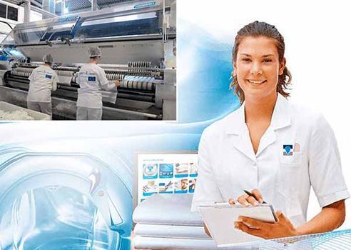 Una mujer con una bata de laboratorio sostiene un portapapeles frente a una lavadora.