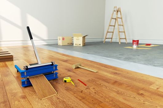 Pose de parquet en bois massif avec outils et matériaux dans une pièce.