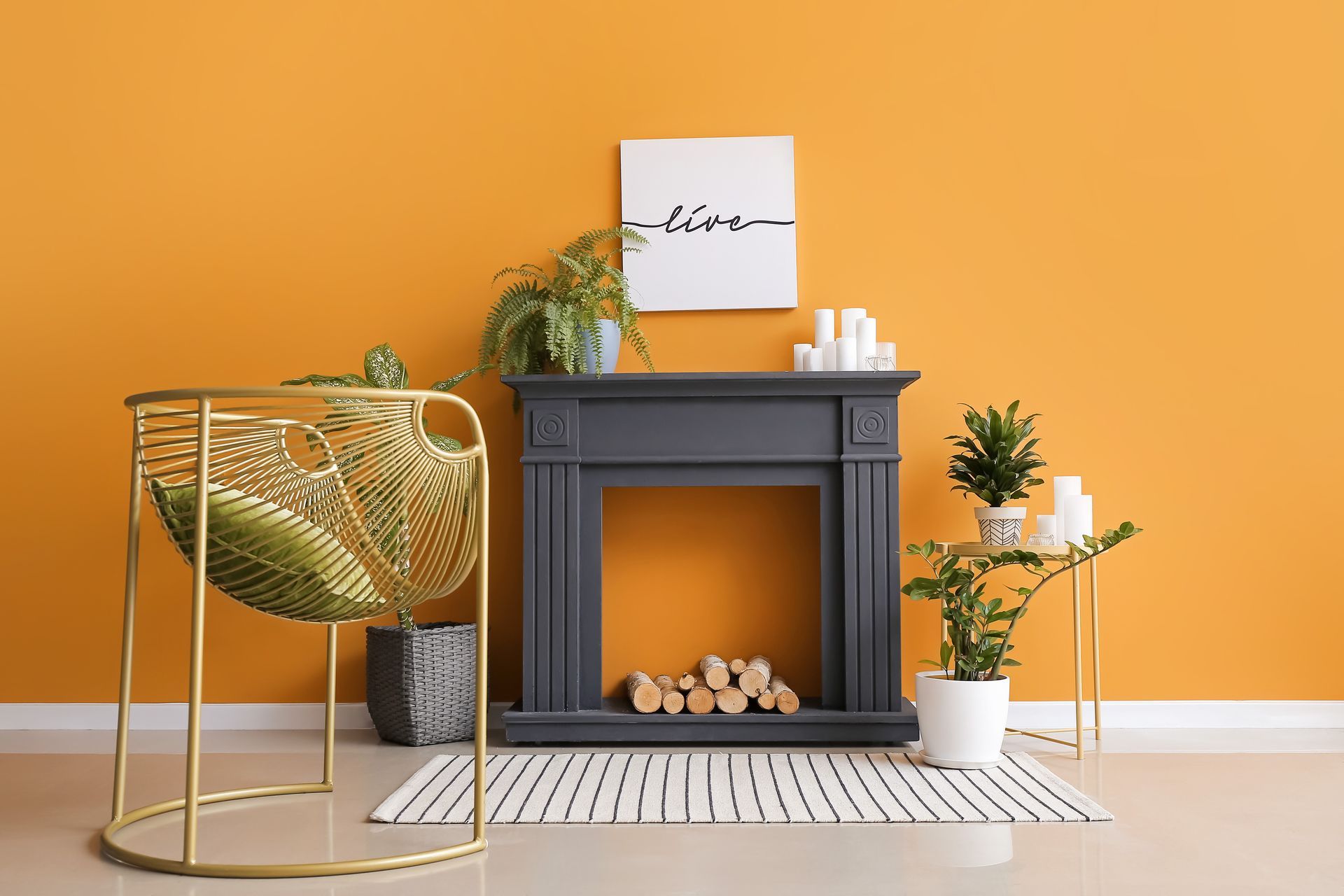 Fauteuil doré avec coussin vert à côté d'une cheminée gris foncé sur un mur jaune orné de plantes et d'éléments décoratifs.