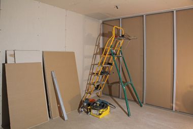 Cloisons sèches et outils dans une pièce avec un escabeau.