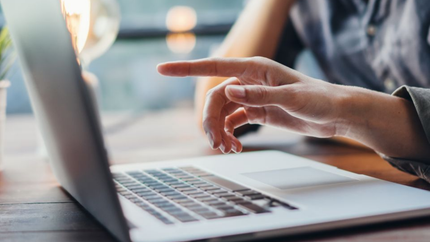 Des mains qui tapent sur un ordinateur portable dans un espace de travail lumineux