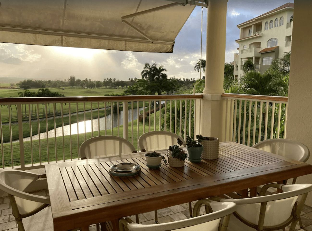 A wooden table and chairs on a balcony overlooking a river