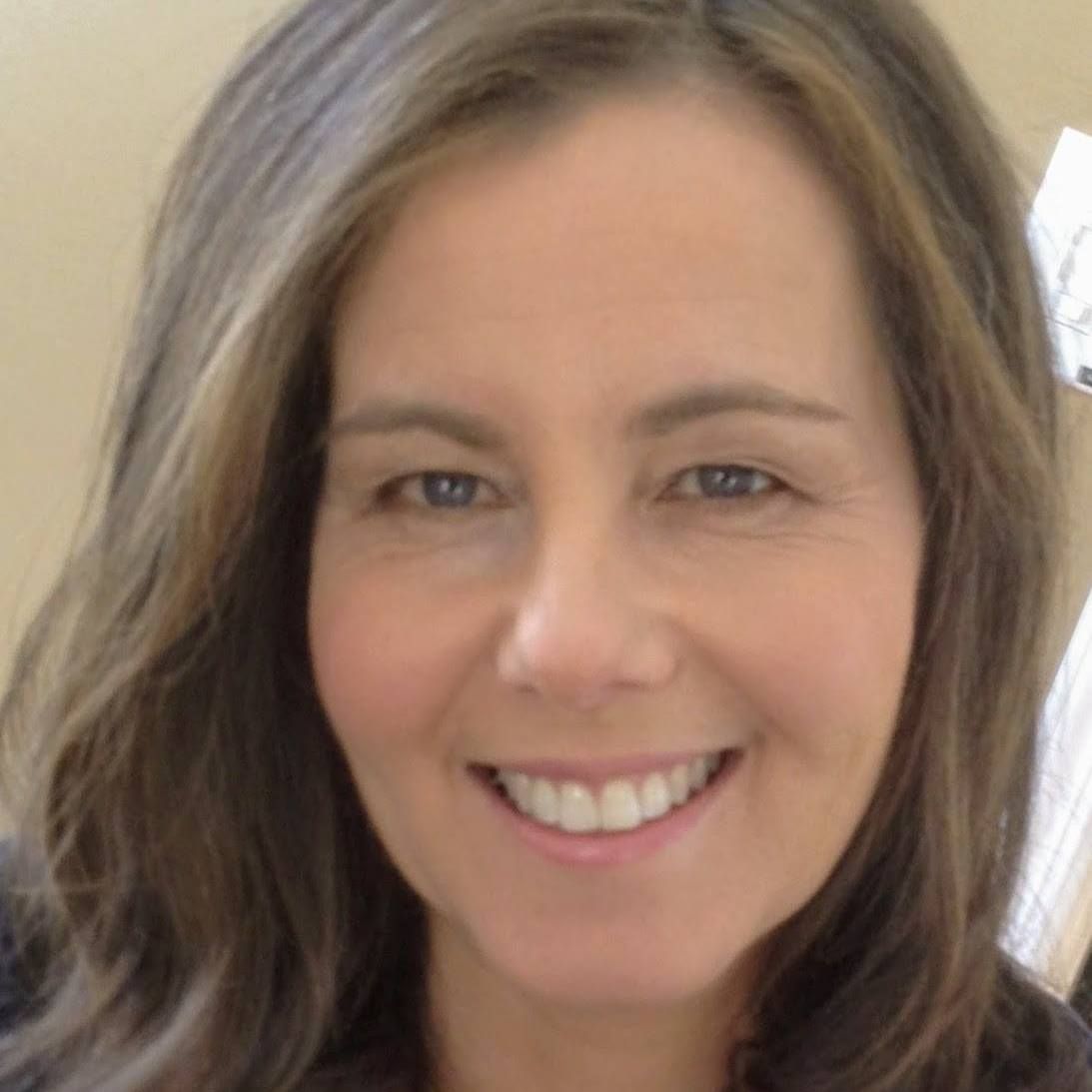A woman with long brown hair is smiling for the camera