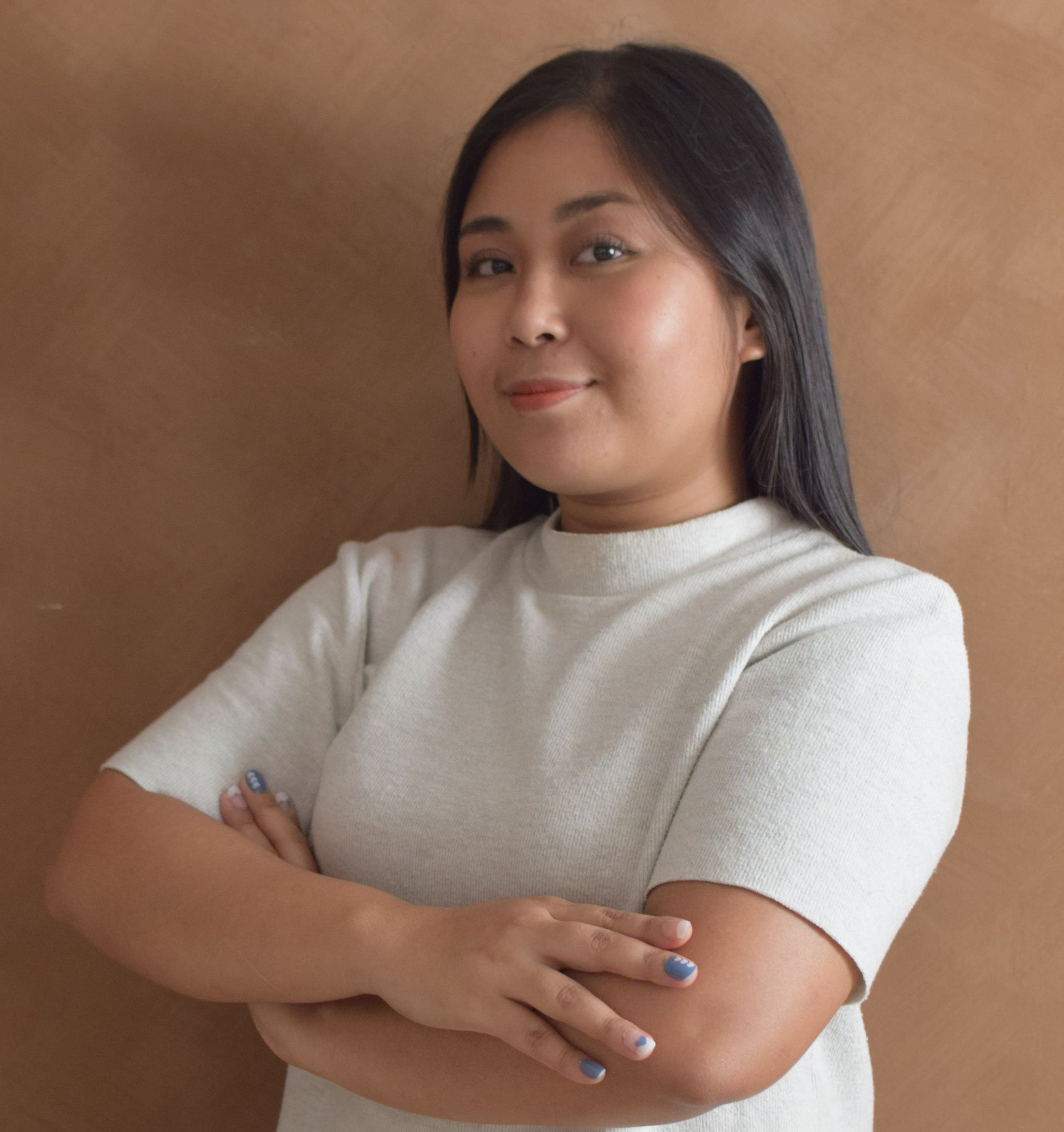A woman in a white shirt is standing with her arms crossed