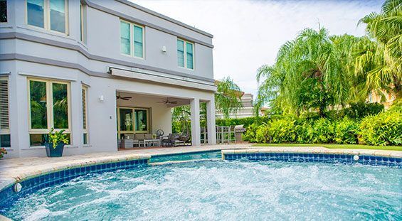 A large house with a large swimming pool in front of it.