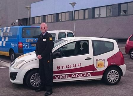 Un hombre parado al lado de un auto que dice vigilancia