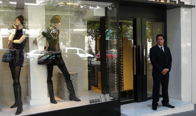 Un hombre con traje y corbata está de pie frente al escaparate de una tienda.