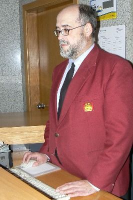 Un hombre con traje rojo y corbata está usando una computadora.