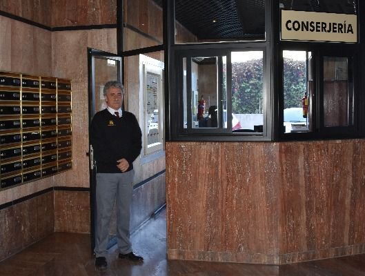 Un hombre parado frente a un cartel de conserjería