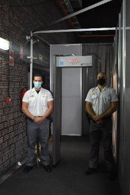 Dos hombres con máscaras están parados frente a un detector de metales.