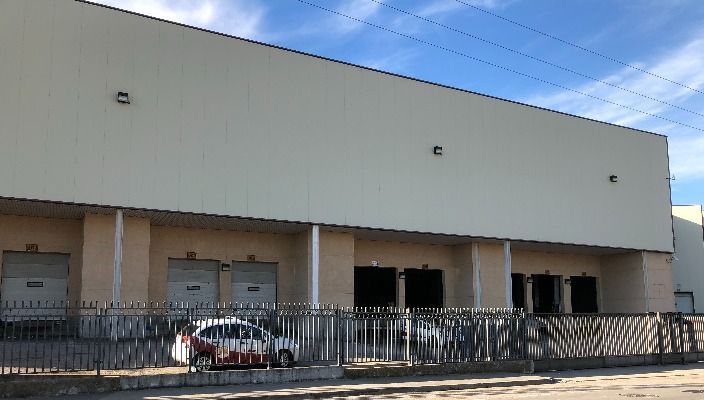 Un edificio blanco con un coche aparcado delante.
