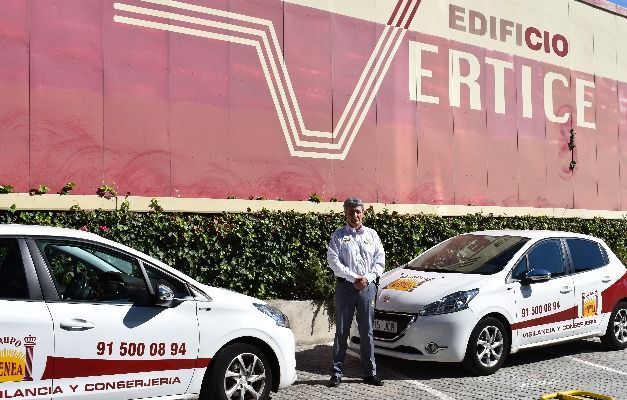 Dos coches blancos están aparcados delante de un edificio que dice edificio vértice