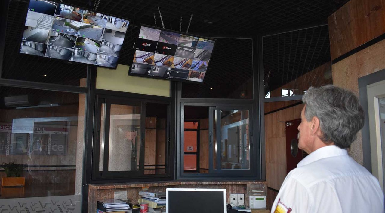 Un hombre con una camisa blanca está parado frente a un monitor de computadora.