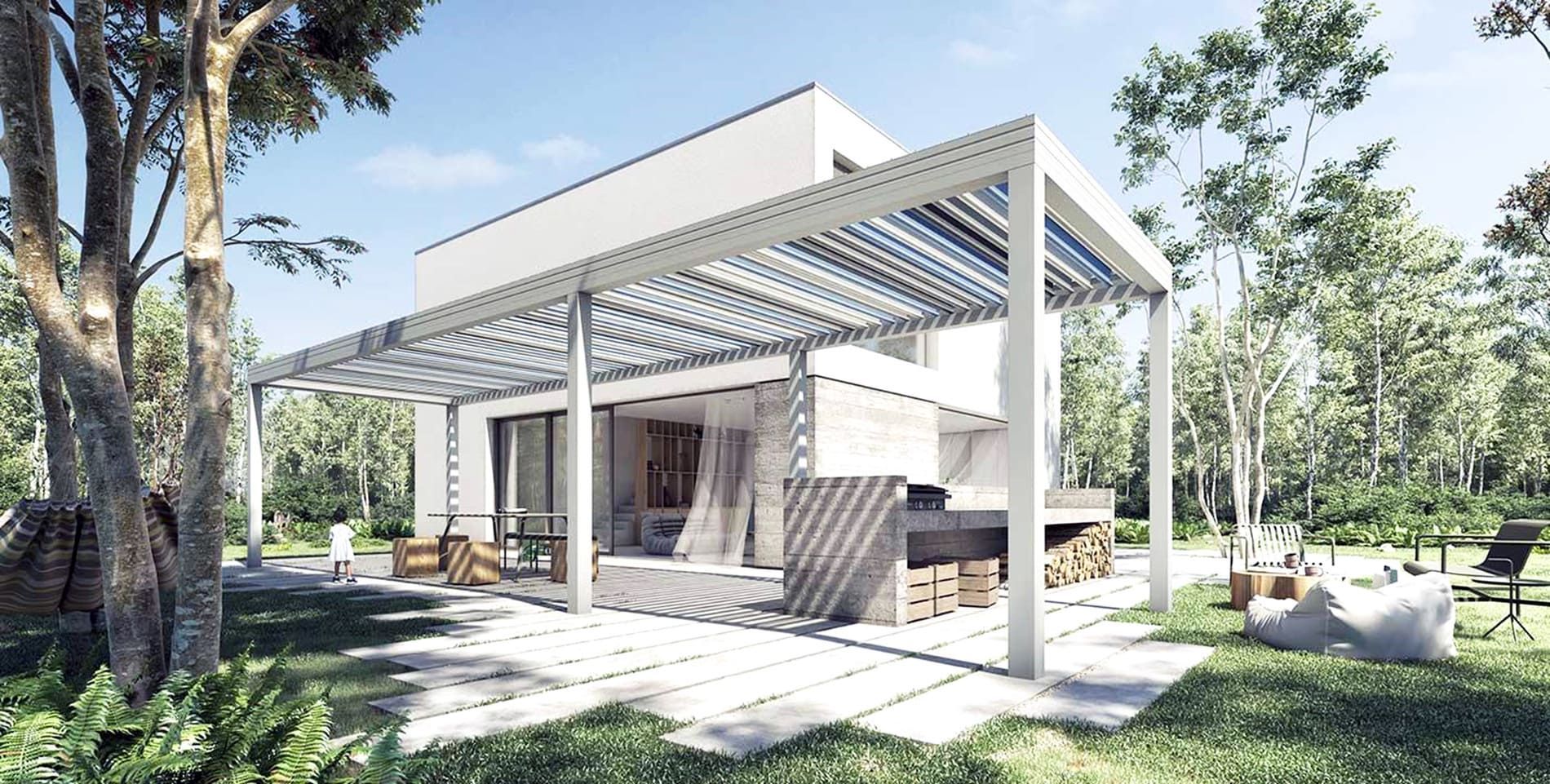 Maison blanche moderne avec pergola dans un jardin boisé, cuisine extérieure, terrasse en pierre.