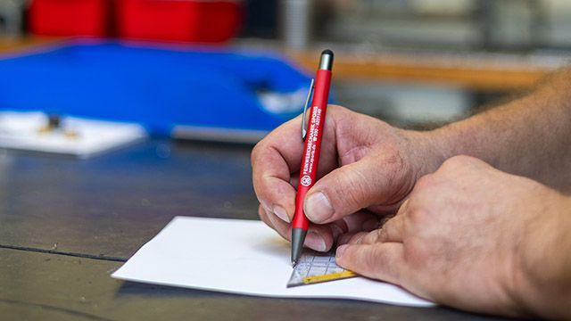 Eine Person schreibt mit einem Stift auf ein Blatt Papier.