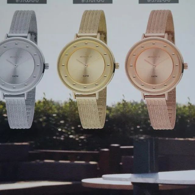 Se muestran tres relojes de diferentes colores sobre una mesa.