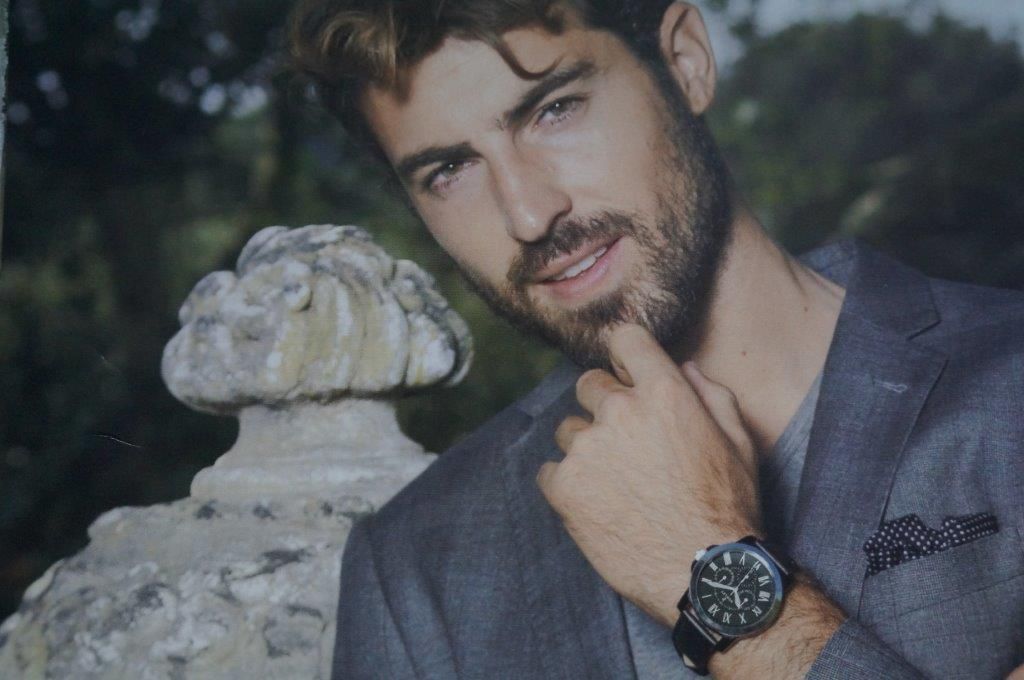 Un hombre con barba lleva un traje y un reloj.