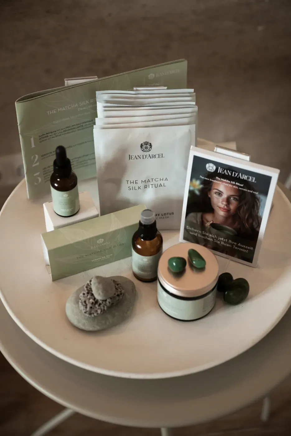 Spa-Geschenkset mit Hautpflegeprodukten, arrangiert auf einem weißen Hocker, inklusive Flaschen, Tütchen, Kerzen und einer Gesichtsmaskenbox