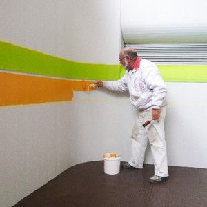 Ein Mann streicht eine Wand mit einem Pinsel. Maler Lüscher GmbH