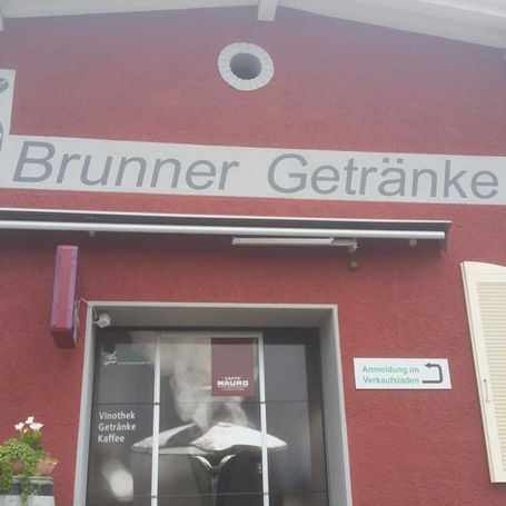 Ein rotes Gebäude mit einem Schild mit der Aufschrift „Brunner Getränke“ darauf, Maler Lüscher GmbH