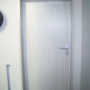 In einem Flur steht neben einem Heizkörper eine weiße Tür. Maler Lüscher GmbH