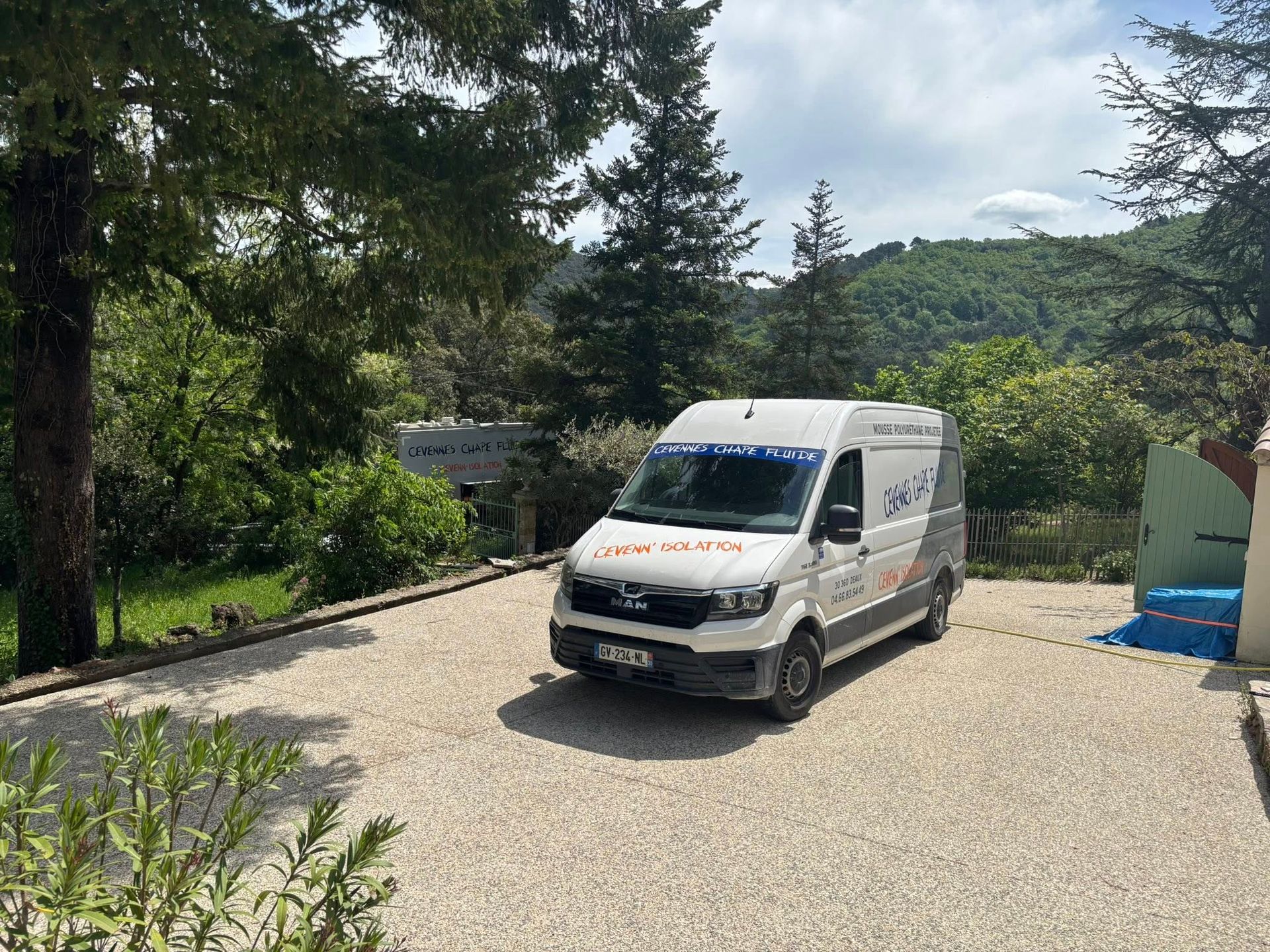 Un camion Cévennes Chape Fluide est garé sur un terrain gravillonné à côté d'un bâtiment clair en construction.