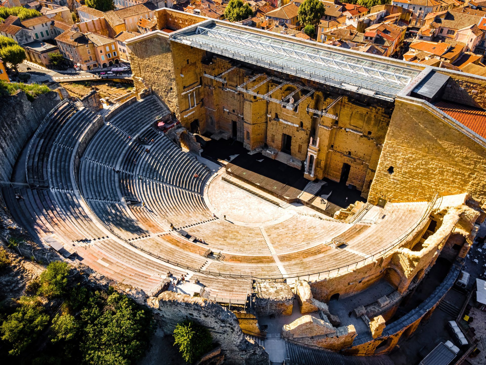 Vue aérienne du théâtre romain d'Orange en France, montrant ses imposants gradins en pierre et son massif mur de scène.