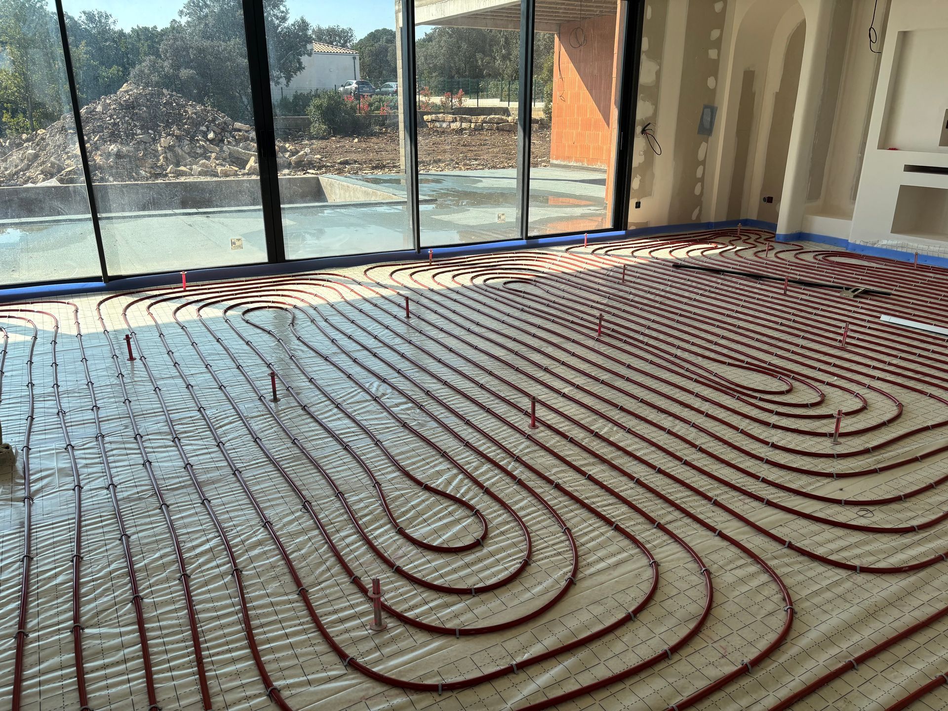 Des tubes rouges pour un système de chauffage au sol radiant sont disposés en boucles.