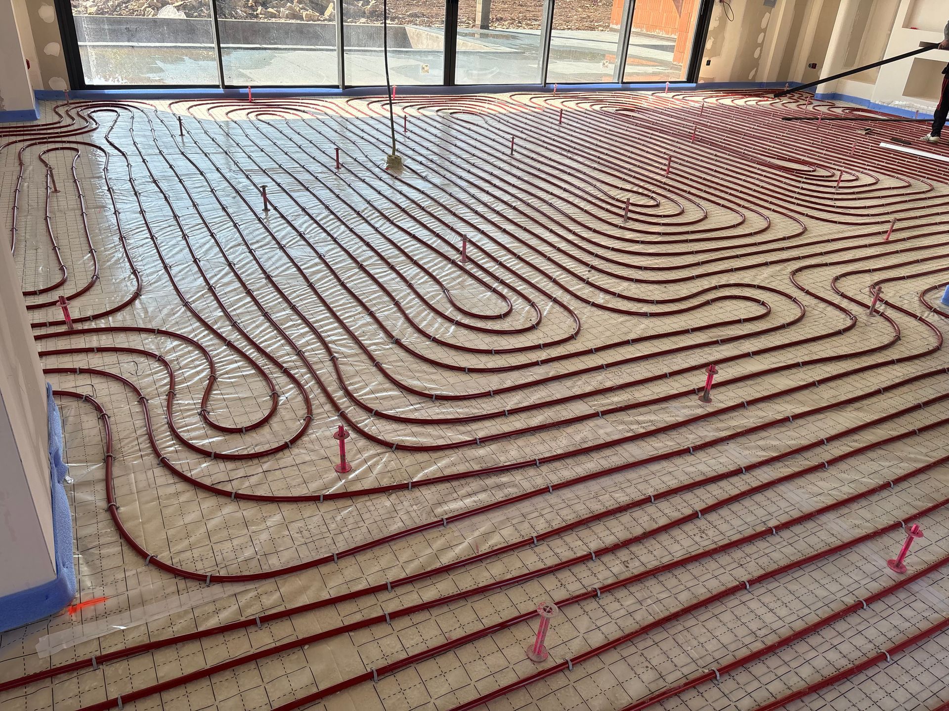 Tuyaux rouges pour chauffage au sol radiant installés avant pose de chape fluide.