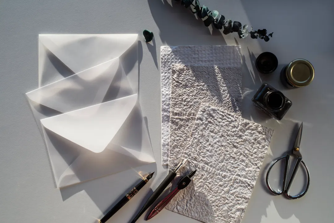 Folleto con cubierta geométrica oscura junto a un cristal transparente sobre una superficie clara.