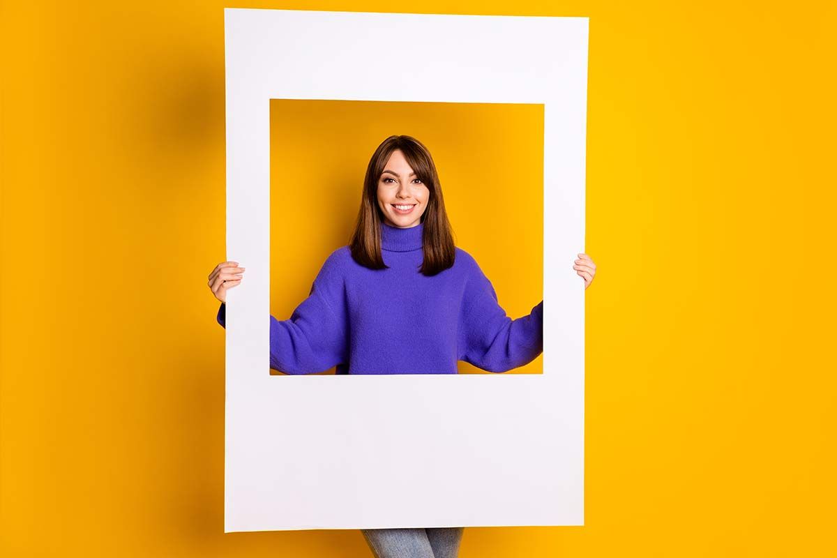 Femme à l'intérieur d'un cadre devant mur jaune