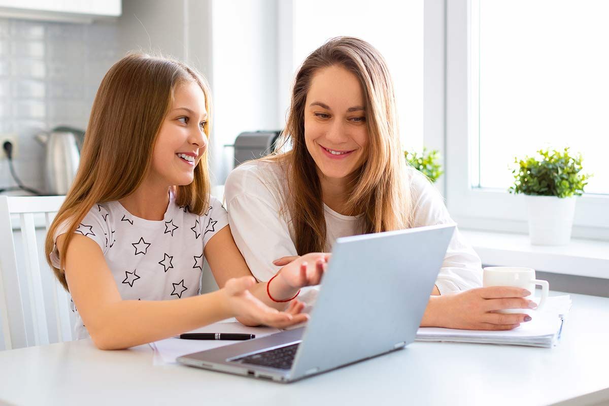 Une mère et sa fille sourient devant un ordinateur portable