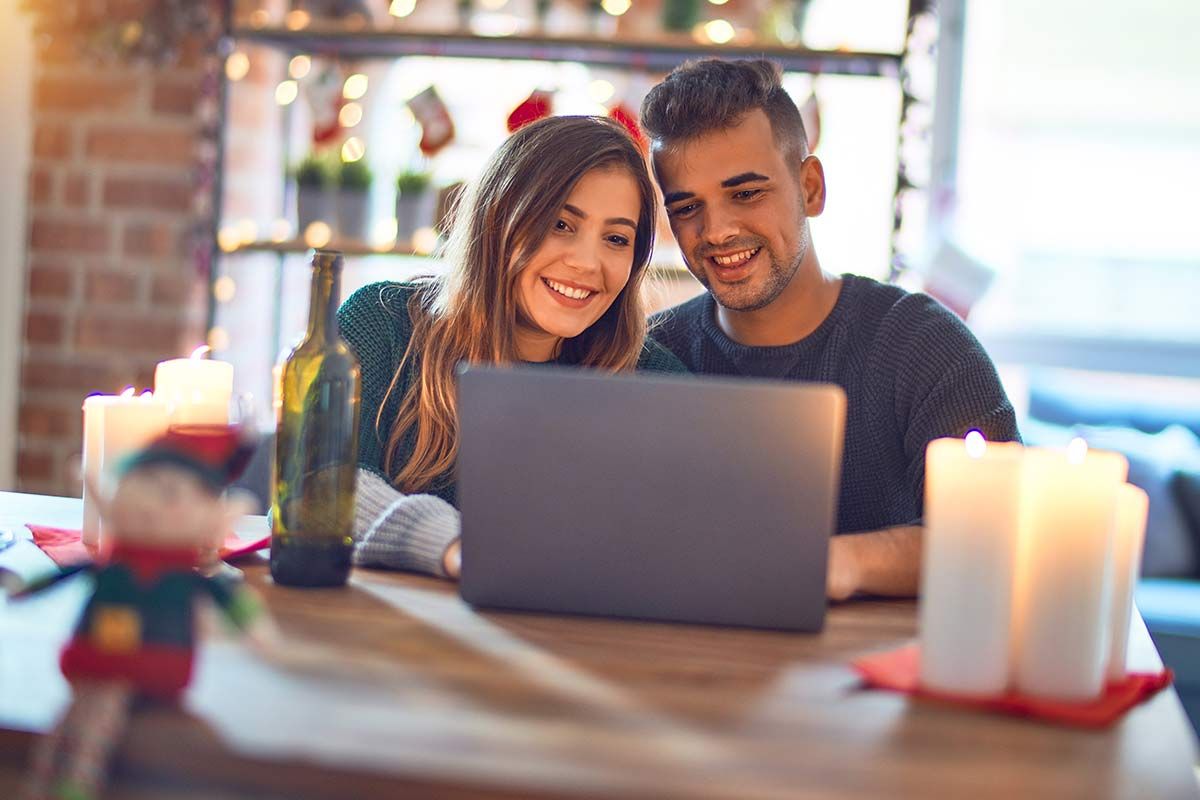 Un couple sourit devant un ordinateur portable
