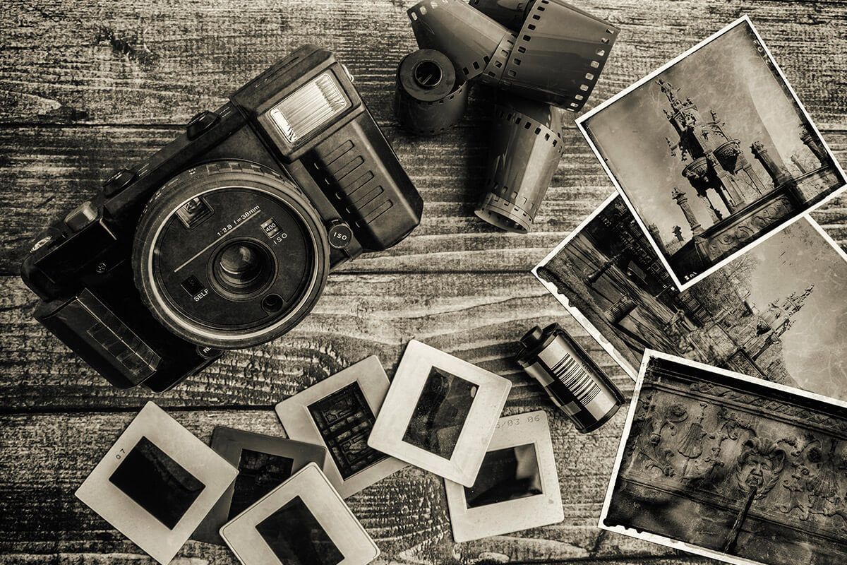 Image en noir et blanc de photographies d'époque et pellicule sur une table en bois