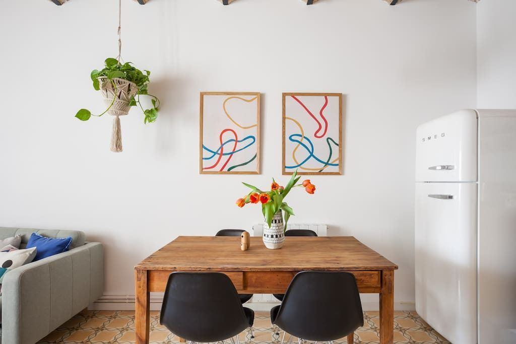 Un comedor con una mesa y sillas de madera y un refrigerador blanco.
