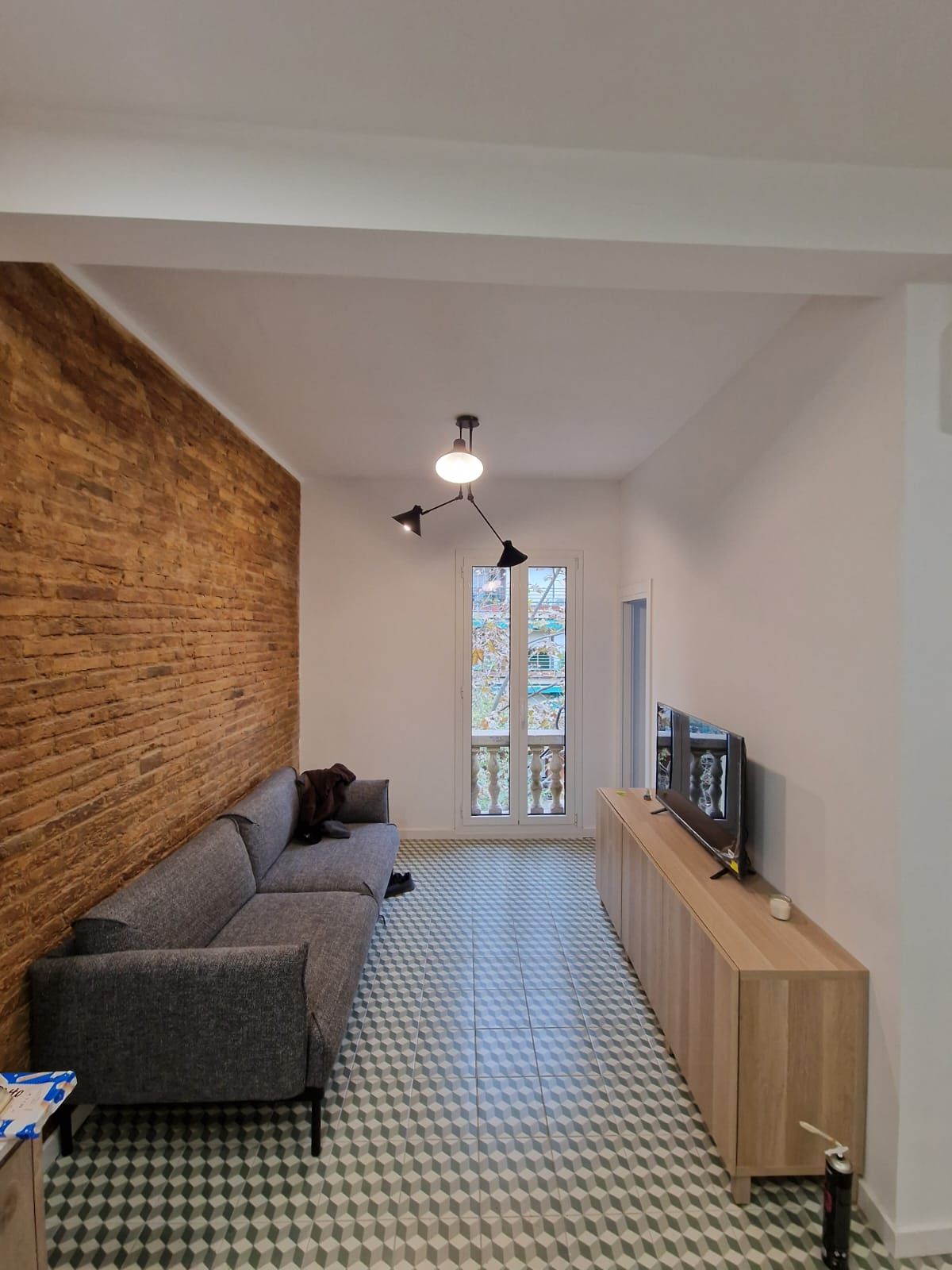 Una sala de estar con un sofá, televisión y una pared de ladrillos.