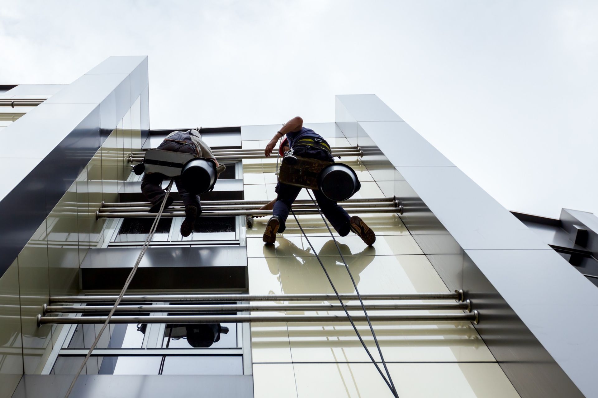 Dos hombres están subiendo por el costado de un edificio alto.