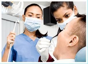Una dentista examina los dientes de un hombre en un consultorio dental.