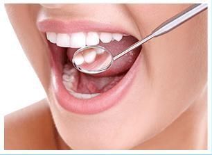 Una mujer se está examinando los dientes con un espejo dental.