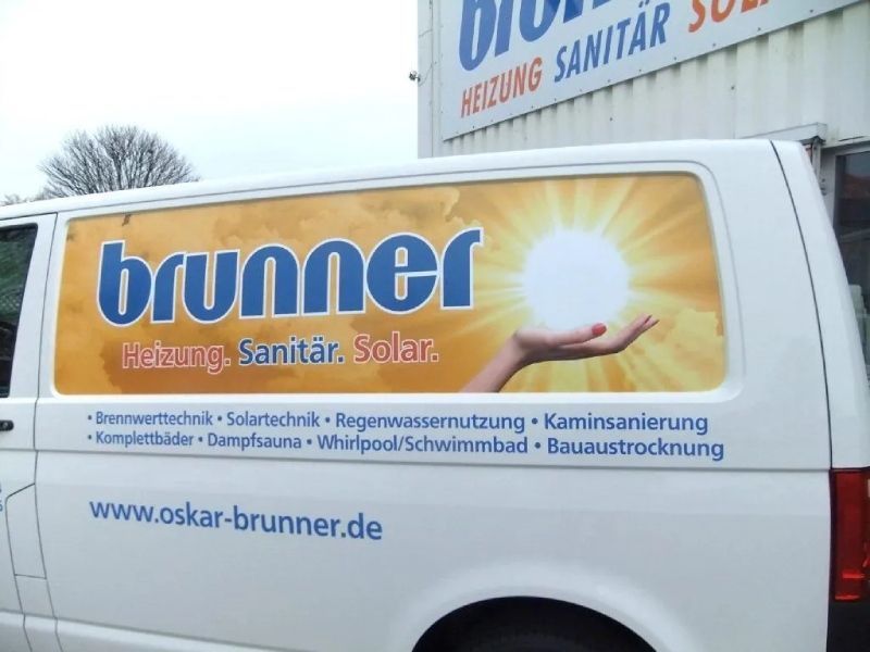 Weißer Lieferwagen mit dem Logo „Brunner“: Hand, die eine Sonne hält, plus Leistungsverzeichnis und Website.